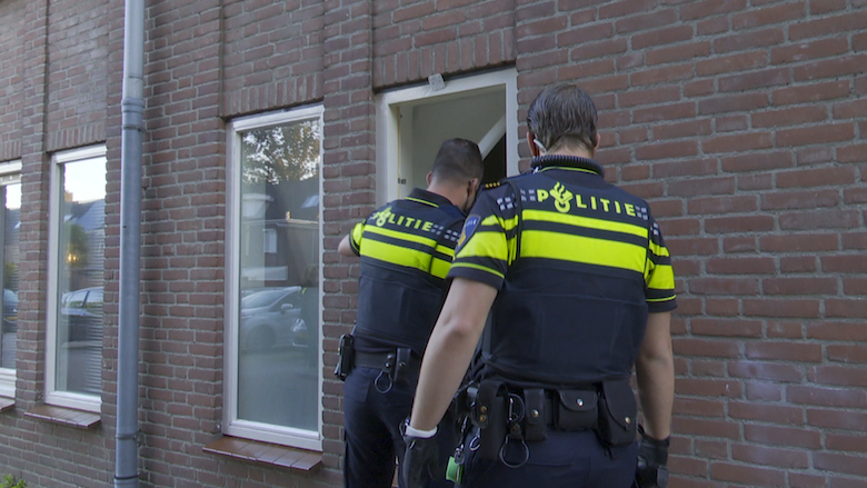 Politieagenten kijken vóór de arrestatie bij Nicky H. door het raam Politieagenten kijken vóór de arrestatie bij Nicky H. door het raam